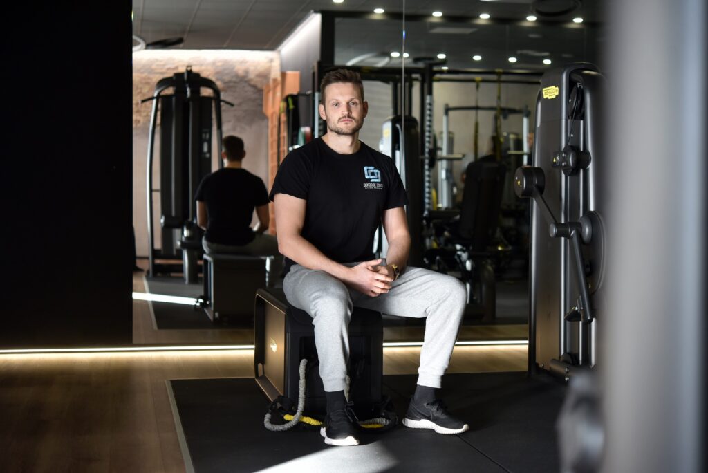 Giorgio De Conto, personal trainer, seduto in palestra con attrezzature fitness